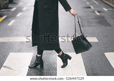 fashion blogger outfit details. fashionable woman wearing a black oversized coat, black jeans, black ankle shoes a black trendy handbag. detail of a perfect fall fashion outfit. 
 Royalty-Free Stock Photo #526447129