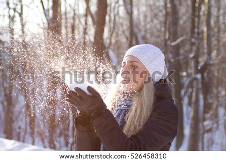 Beauty Winter Girl Blowing Snow in frosty winter Park. Outdoors. Flying Snowflakes. Sunny day.
