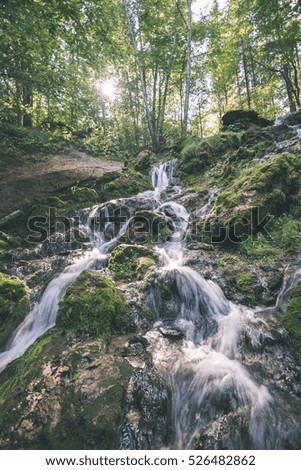 rocky waterfall in summer with stream and low water in forest- vintage retro look