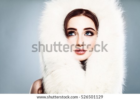 Winter Beauty. Beautiful Winter Woman with Makeup and White Fur Looking Up