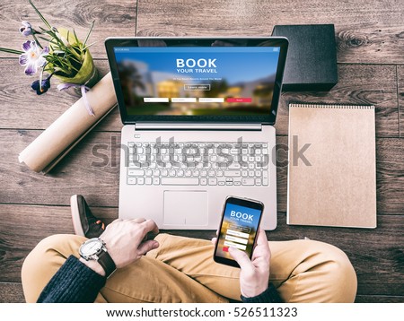 Man using a laptop and smartphone for booking hotel online. Tour reservation, Screen graphics are made up. Royalty-Free Stock Photo #526511323