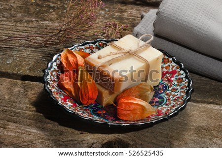 couple bars of handmade soap on oriental plate with several fruits of physalis Royalty-Free Stock Photo #526525435