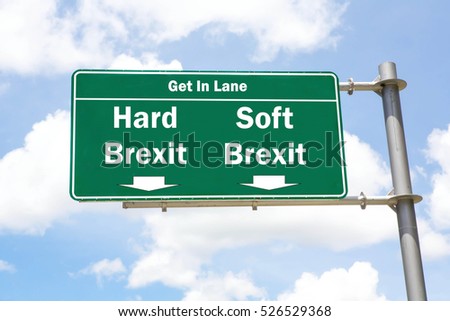 Green overhead road sign with the instruction to get in lane with a Hard Brexit or Soft Brexit concept against a partly cloudy sky background. Royalty-Free Stock Photo #526529368