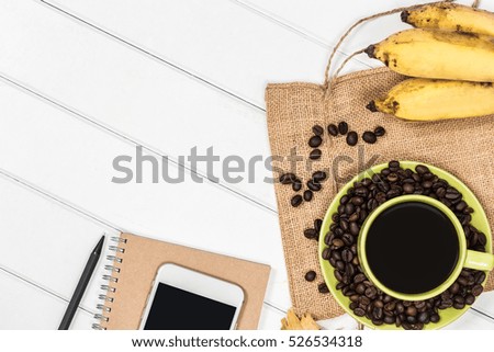 Modern white wooden desk with coffee cup and coffee bean and banana with copy space for input your product or text.