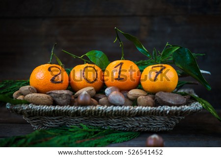 New Year 2017 is Coming Concept. Numbers written in Black Ink on the Oranges that are laying in the Basket with Pine Sticks and Nuts, Rustic Background