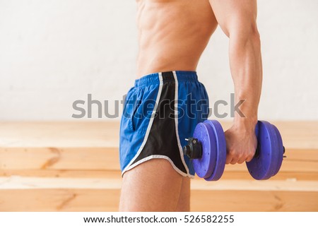 Close up picture of male sportsman abs with dumbbell