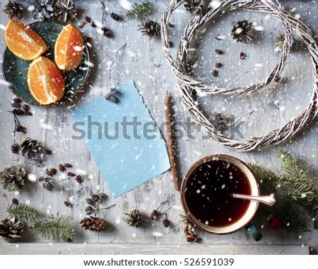 Holidays background. Snowfal. Blank paper Christmas card with brown envelop and pine cones on old wooden table. cup of coffee, oranges, pencil, pine nuts, New year. selective focus and toned image
