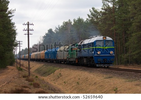 Freight train hauled by two diesel locomotives passing the forest