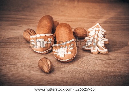 Merry Christmas and Happy New Year card - gingerbread slippers and  decorated Christmas tree, walnuts on wooden table - desktop view design
