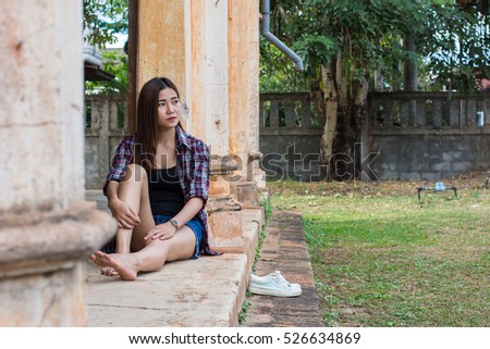 Asian woman sitting on the cement floor. In the old building.