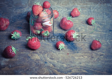 Lots of fresh bright red strawberries and glass jar. Selective focus. Shallow depth of field. Toned.