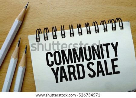 Community Yard Sale text written on a notebook with pencils