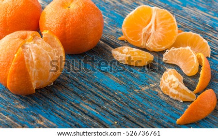 mandarines, peeled tangerine and tangerine slices on a blue wooden table