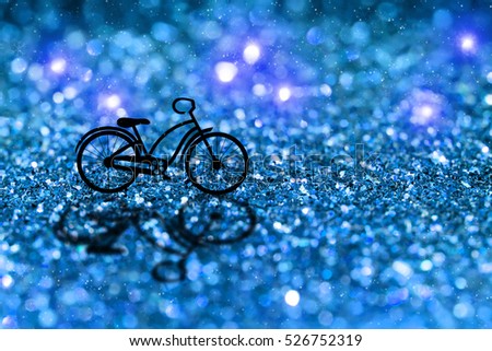 Silhouette of a bicycle in christmas night with blue glitter bokeh and snow abstract background.