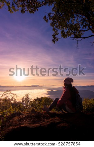 Traveling woman with backpack watching the mist and beautiful sky with sky clouds at sunrise.