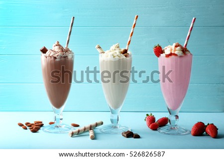 Delicious milkshakes on blue wooden background Royalty-Free Stock Photo #526826587