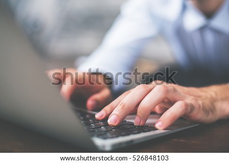 Side view of male hands typing on laptop keyboard