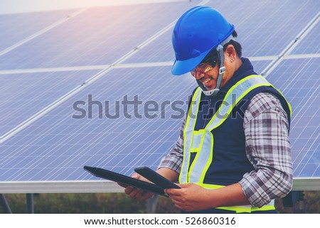 electrician working on maintenance equipment at industry solar power; engineer use smartphone connect to portable solar panel.