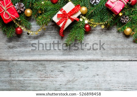 christmas background with fir tree branches, decorations and gift boxes  over rustic wooden background. top view