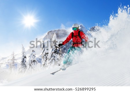 Freeride skier with rucksack running downhill in freeze motion of snow powder. Royalty-Free Stock Photo #526899295