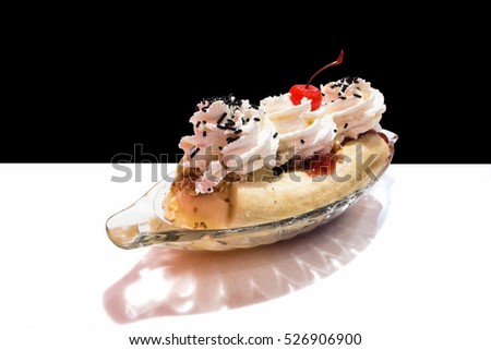 Ice cream, Banana split in a glass bowl on white table and black background.(with warm light effect)