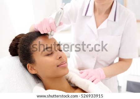 Beautician performs a needle mesotherapy treatment on a woman's face  Royalty-Free Stock Photo #526933915