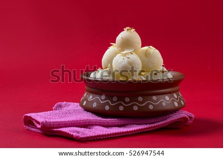 Indian Sweet or Dessert - Rasgulla, Famous Bengali sweet in clay bowl with napkin on Red Background Royalty-Free Stock Photo #526947544