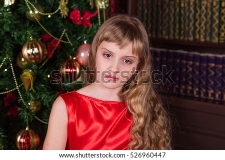 Lovely girl in a long red dress at the Christmas tree. Portrait of girl in Christmas decorations