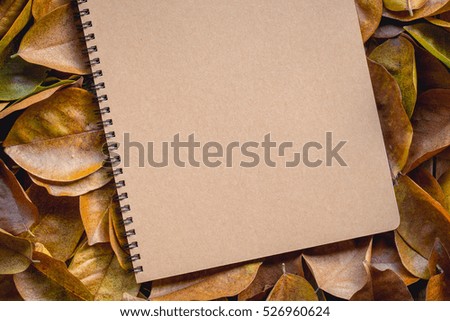 Vintage picture tone of Autumn background. The fallen autumn leaves and notebook on wooden garden table. can used add text message or greeting card.