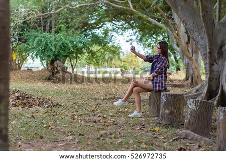 Asian woman shooting herself with mobile phone.