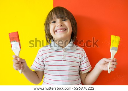 Child painting the home wall in colors