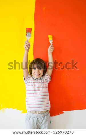 Child painting the home wall in colors
