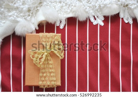 Top view of golden gift box on red and white stripe background with copyspace