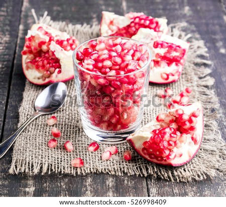 Fresh pomegranate seeds in glass Wooden background