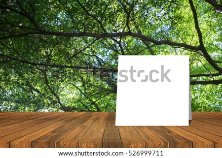 white card put on Wooden desk or wooden floor on green bokeh background.use for present or mock up your product.clipping path include