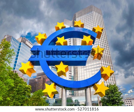 Euro sign at European Central Bank headquarters in Frankfurt, Germany with dark dramatic clouds symbolizing a financial crisis Royalty-Free Stock Photo #527011816