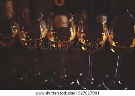 Row of glasses of white wine Chardonnay in a bar or restaurant in the background bottles with alcohol. Selective focus