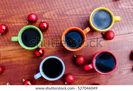 Cup of coffee and christmas balls on wooden table.