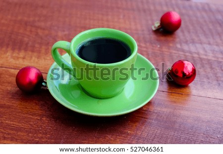 Cup of coffee and christmas balls on wooden table.