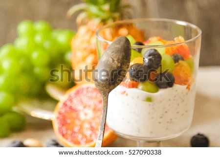 white yogurt with chia seeds red oranges, blueberries and pistachios on a background of pineapple, grapes