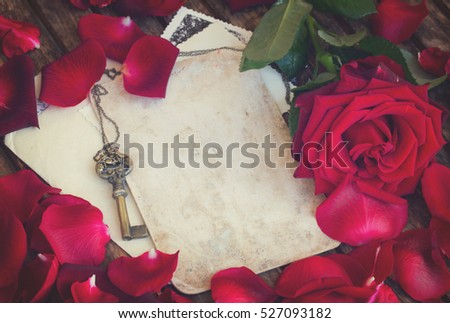 vintage background with red rose petals and antique gold key, retro toned
