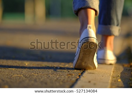 Woman jeans and sneaker shoes walking on the road sunset light Royalty-Free Stock Photo #527134084