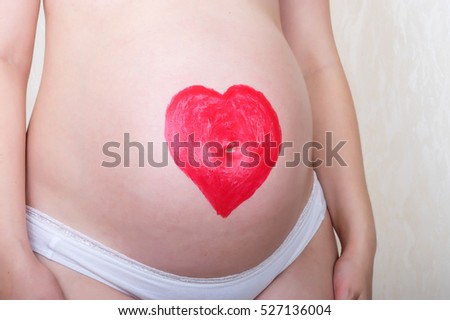 Heart drawn in lipstick on a stomach of the pregnant woman