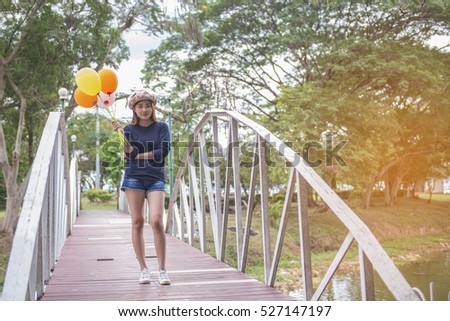Happy Beautiful woman with balloons standing on the bridge in the park.