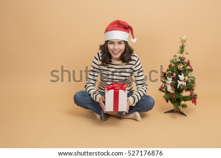 Beautiful christmas girl in santa hat with boxes  on autumn background.