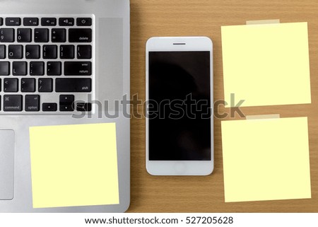 Working with modern devices, digital tablet computer and mobile phone on wooden plate with empty blank note on wooden table background.business concept