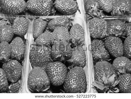 Ripe strawberries in a container on the counter of a shop. Old style, black - white photo.