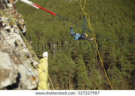 A man jumps into the abyss with a rope from a cliff. Ropejumping.