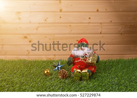 Santa claus doll in Christmas day on green grass and wood background. Morning sunshine  day and good day.
