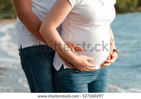 Close up of human hands holding pregnant belly
